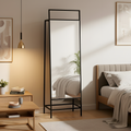 Black floor mirror in a bedroom setting with a bed and decor.
