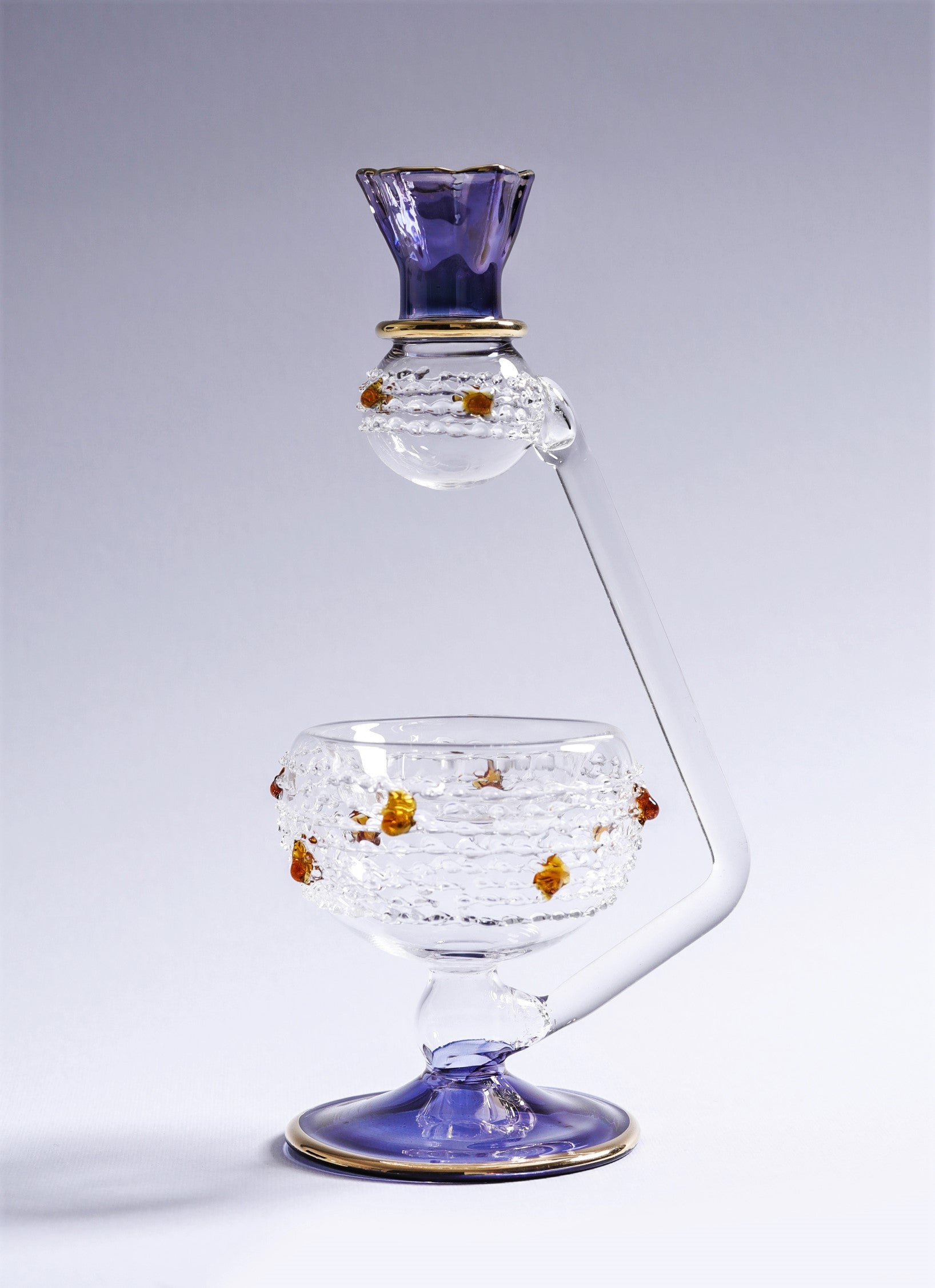 Decorative glass piece with purple and gold accents on a light gray background