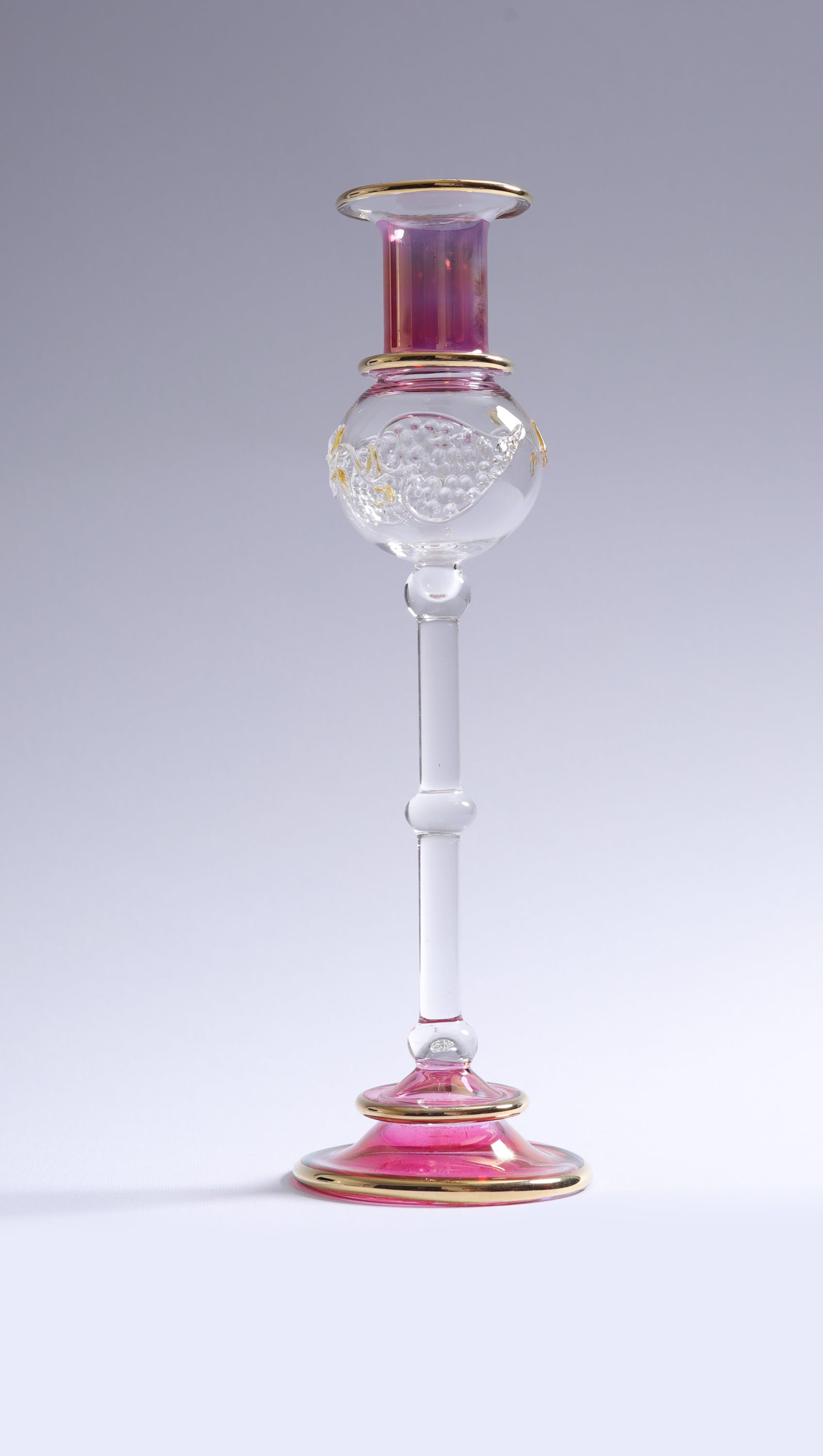 Decorative glass candlestick with pink and gold accents on a white background