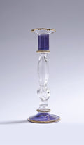 Decorative glass candlestick with a purple candle on a gray background
