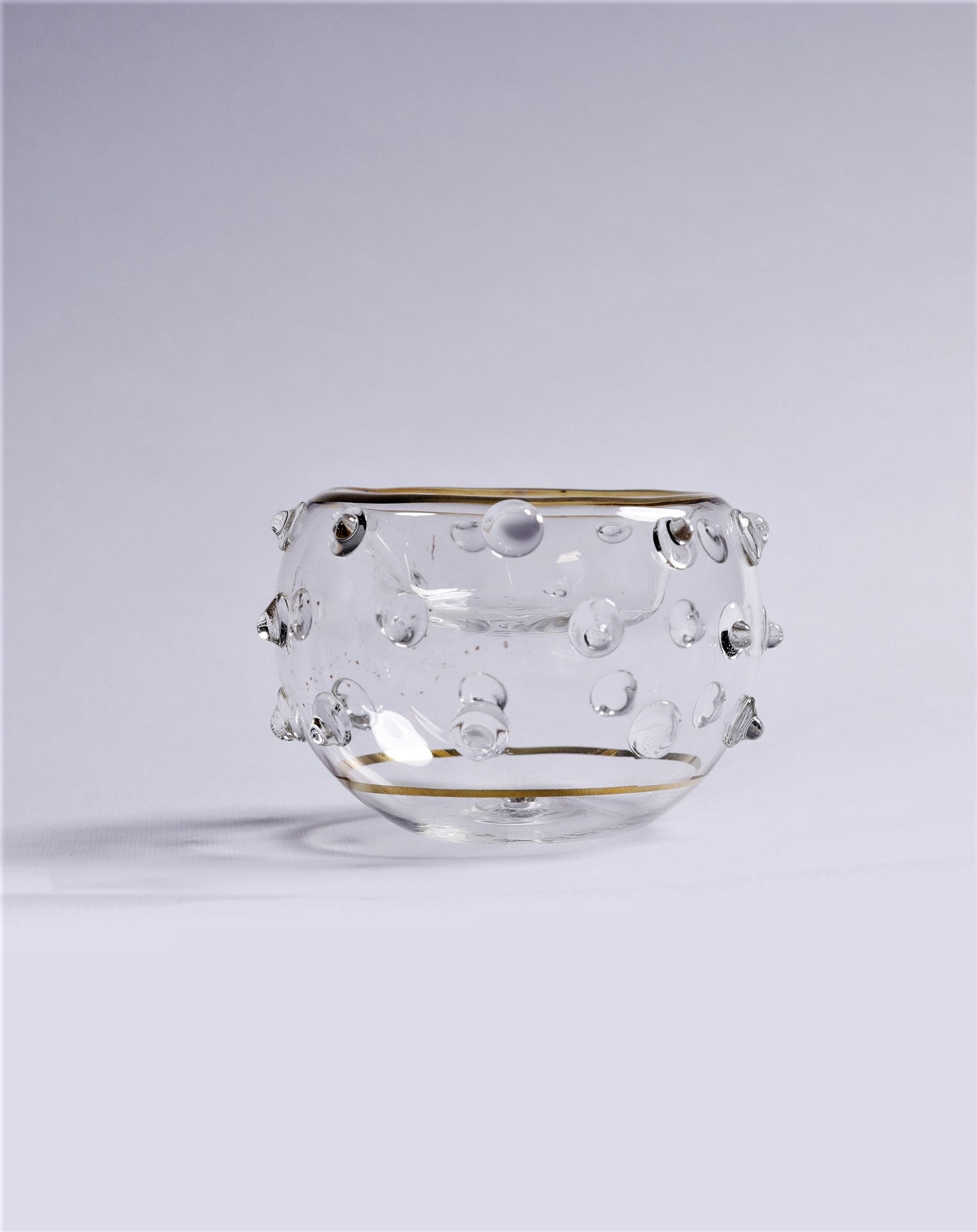 Clear glass bowl with gold rim on a light gray background