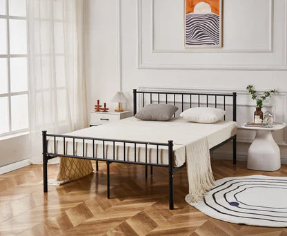 Black metal bed frame in a bedroom with wooden flooring and decorative elements.