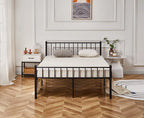Bedroom with a black metal bed frame, white mattress, and decorative items on a wooden floor.