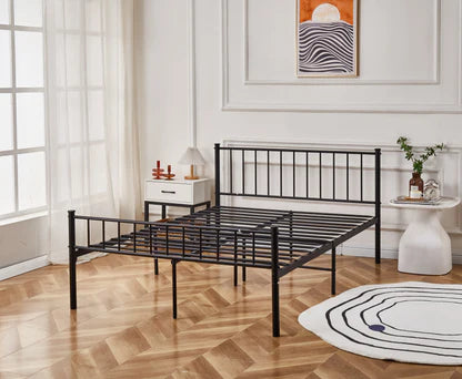 Black metal bed frame in a room with wooden flooring and a window.