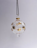 Decorative glass ornament with gold star designs on a gray background