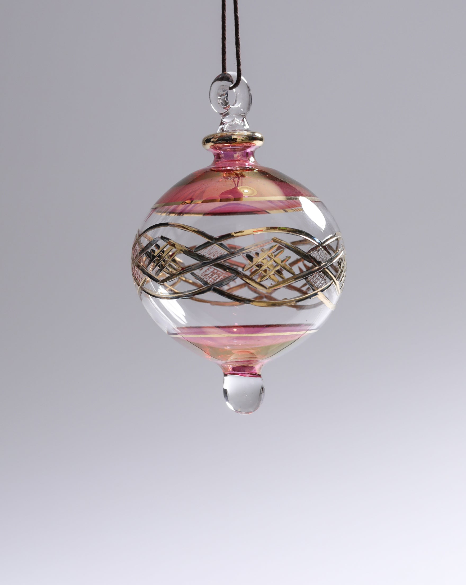 Decorative glass ornament with pink and gold patterns on a gray background