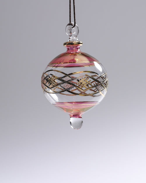 Decorative glass ornament with pink and gold patterns on a gray background