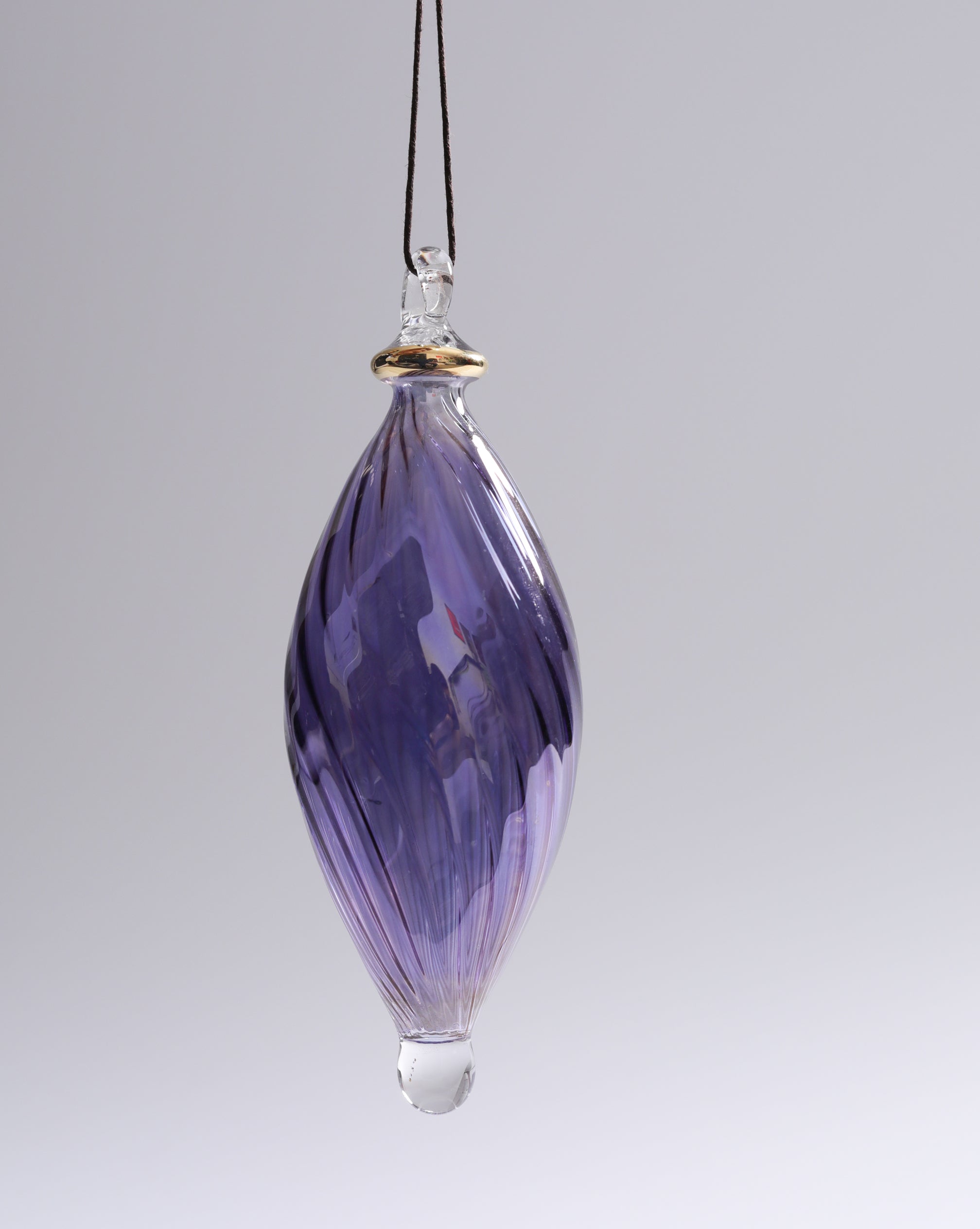 Purple glass hanging ornament on a gray background
