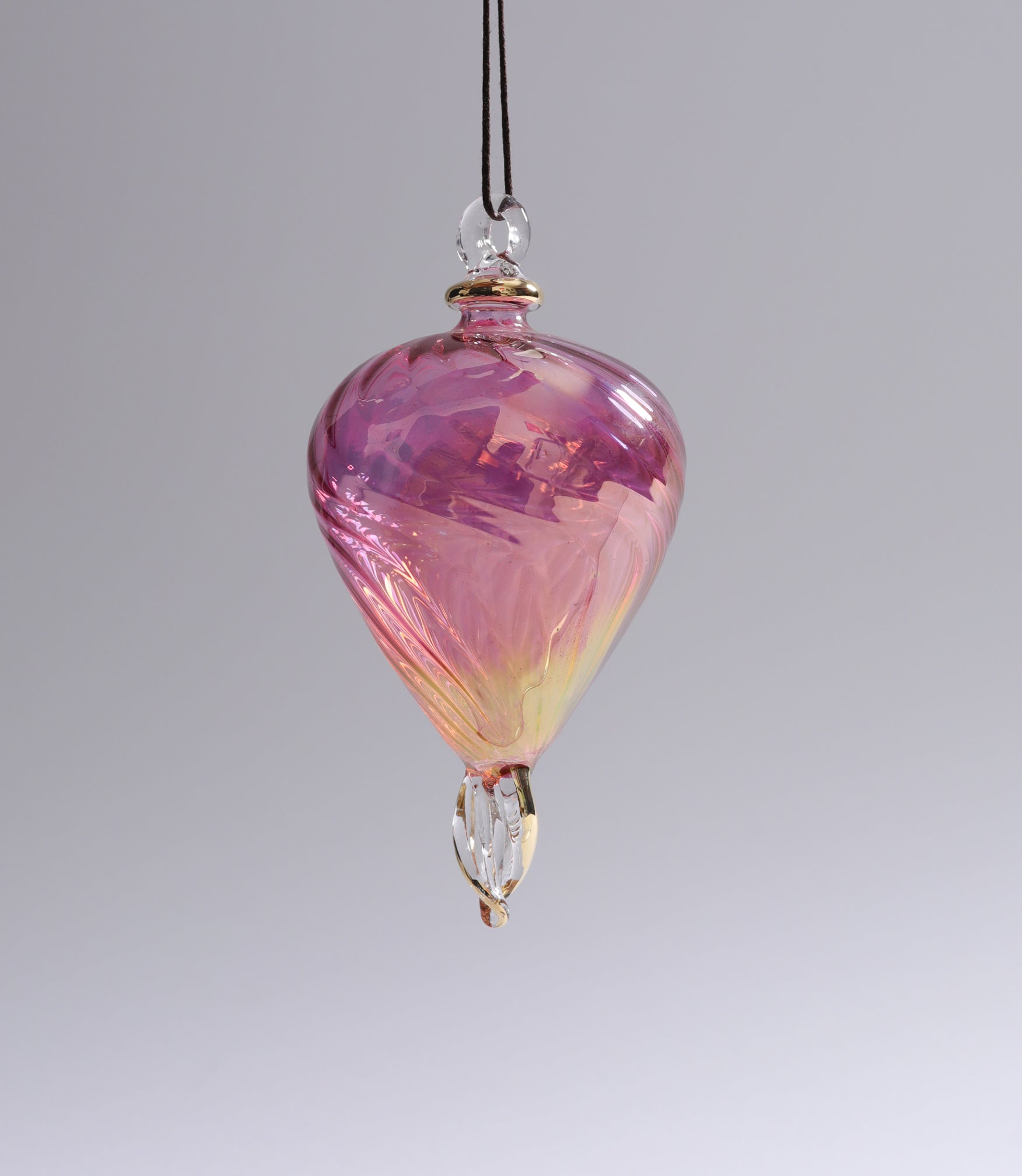 Pink and yellow glass ornament on a gray background