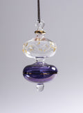 Decorative glass hanging ornament with purple base and gold accents on a gray background