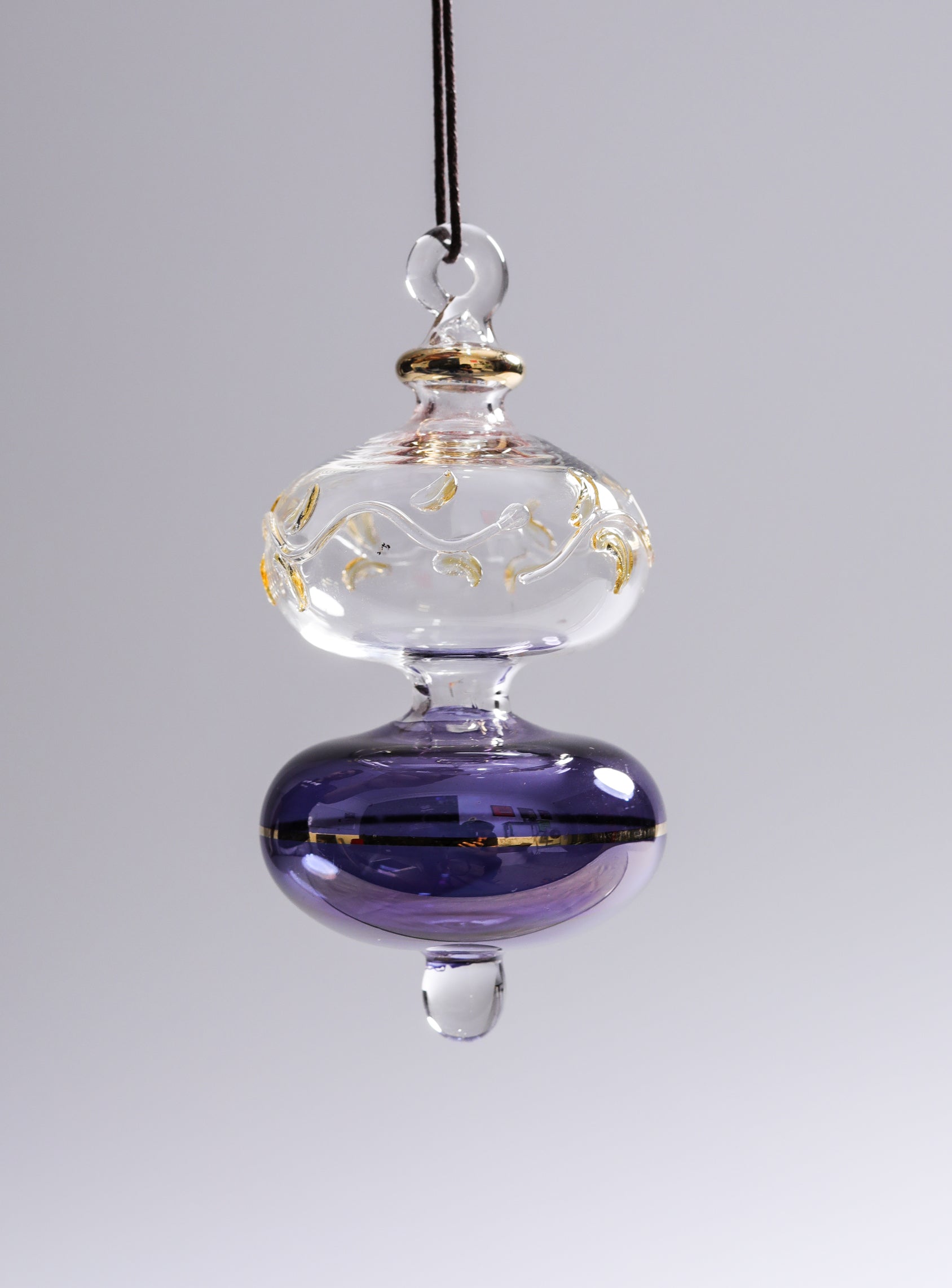 Decorative glass hanging ornament with purple base and gold accents on a gray background