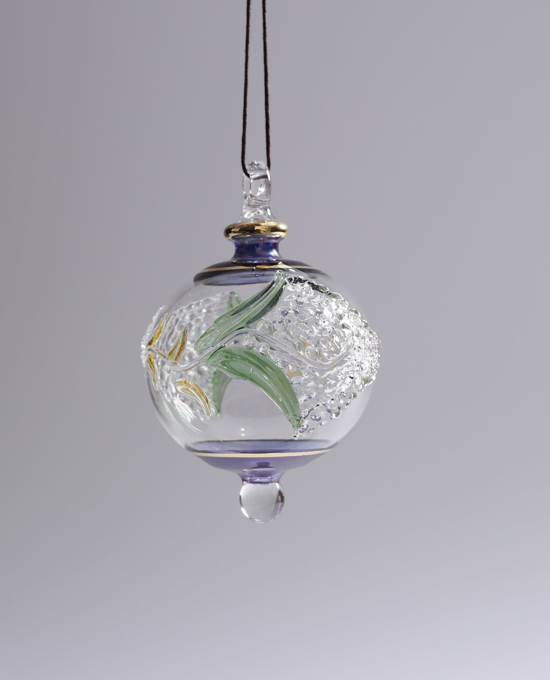 Decorative glass ornament with floral design on a gray background
