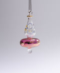 Glass ornament with pink base and clear top on a gray background
