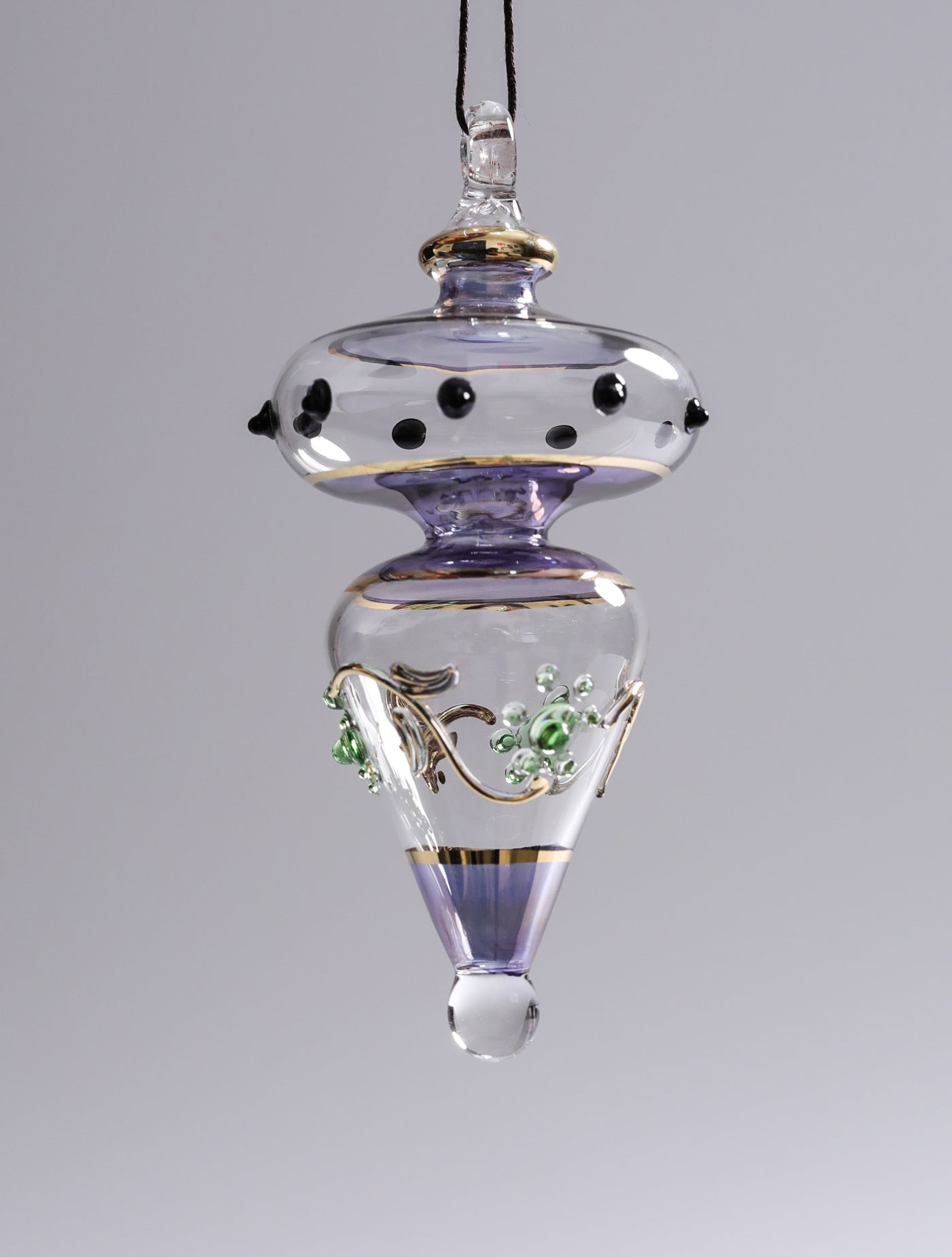 Decorative glass ornament with purple and gold accents on a gray background