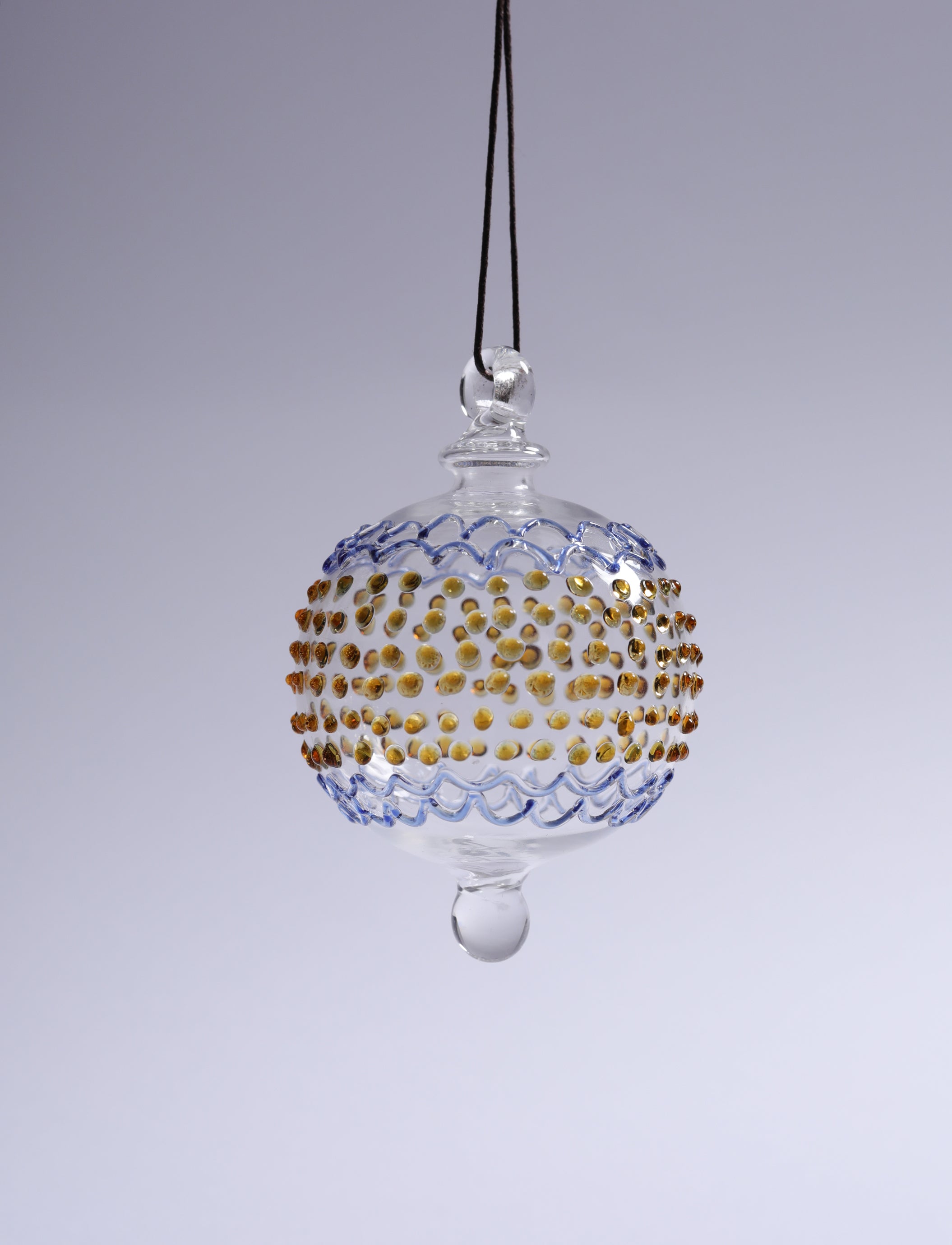 Decorative glass ornament with gold and blue patterns on a gray background