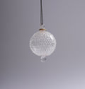 Clear glass ornament with textured surface and teardrop design on a gray background