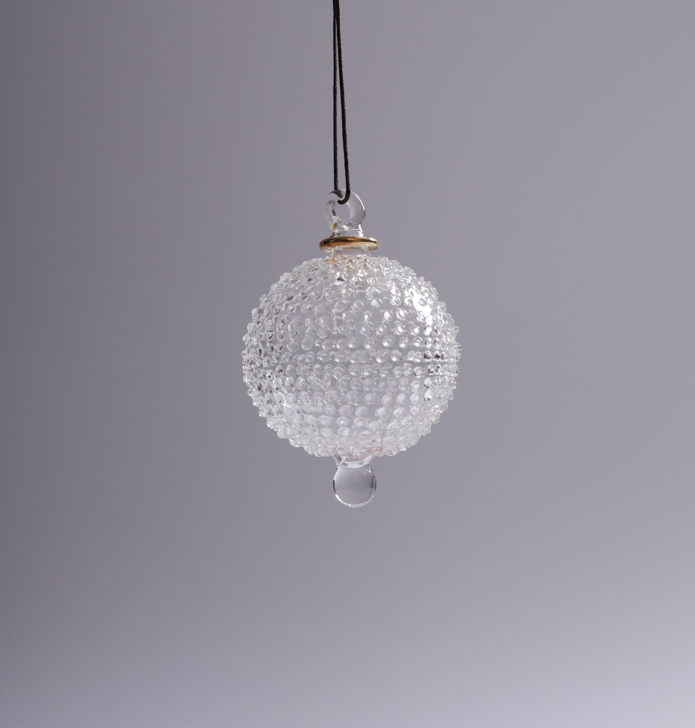 Clear glass ornament with textured surface and teardrop design on a gray background