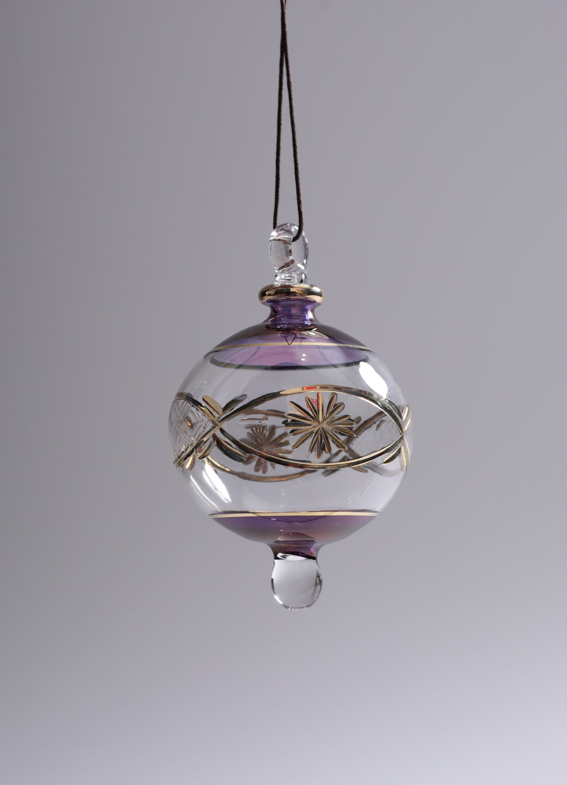 Decorative glass ornament with floral design on a gray background
