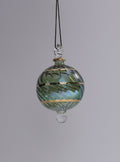 Decorative glass ornament with green and gold patterns on a gray background