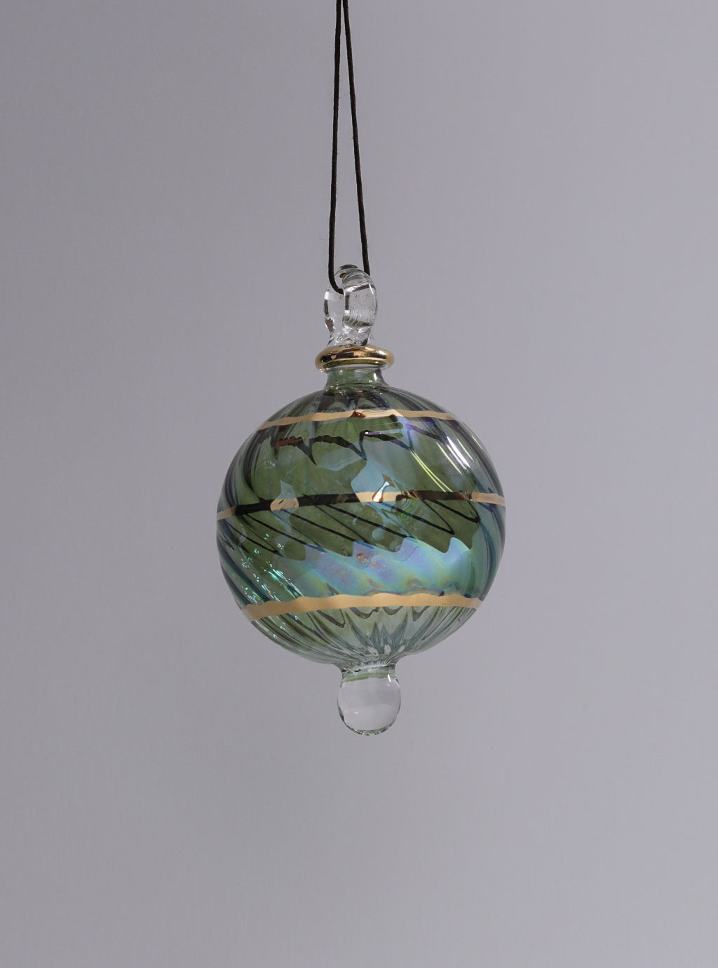 Decorative glass ornament with green and gold patterns on a gray background