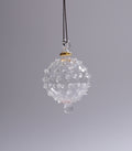 Clear glass ornament with textured surface on a gray background