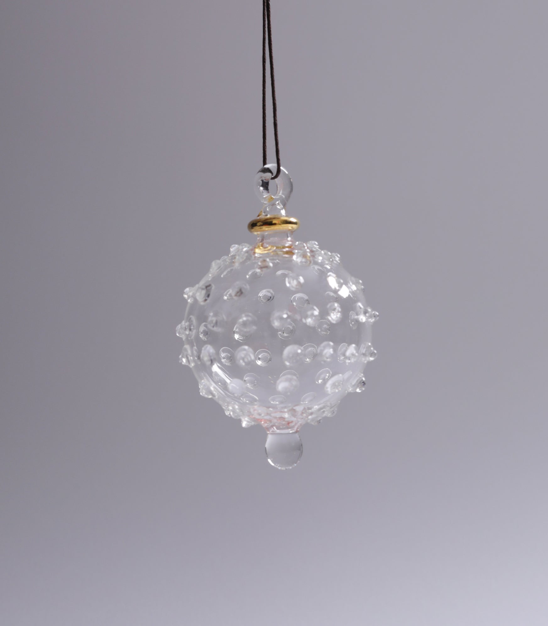 Clear glass ornament with textured surface on a gray background