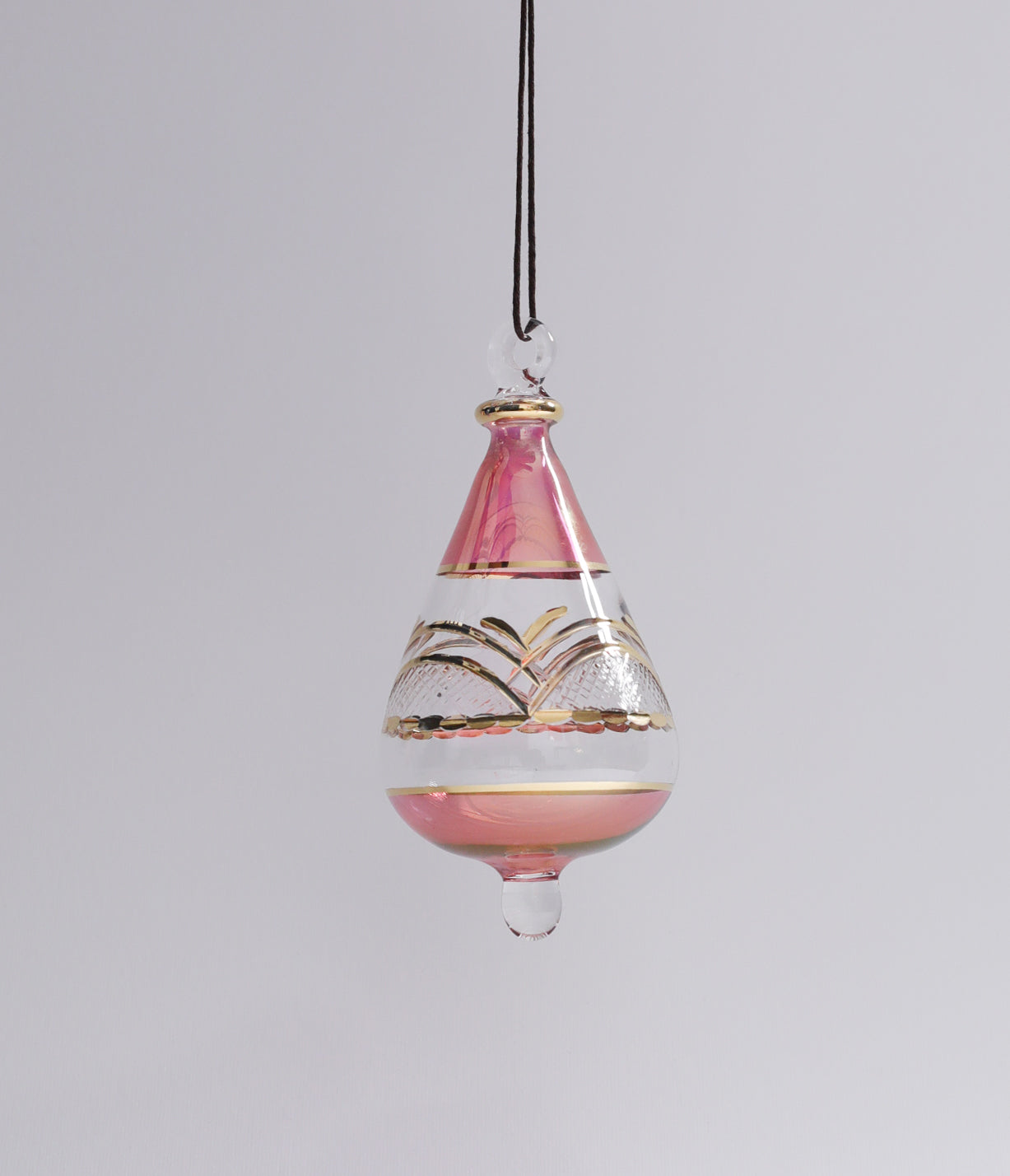 Decorative hanging glass ornament with pink and gold design on a gray background