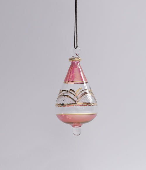 Decorative hanging glass ornament with pink and gold design on a gray background