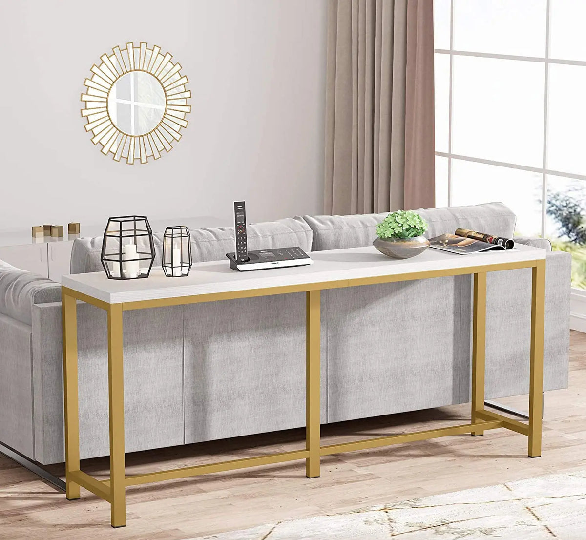 Modern living room with a gold console table, gray sofa, and decorative mirror.