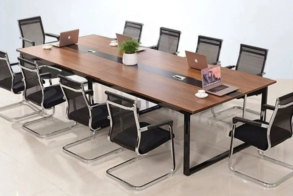 Conference room setup with a long wooden table and black chairs.