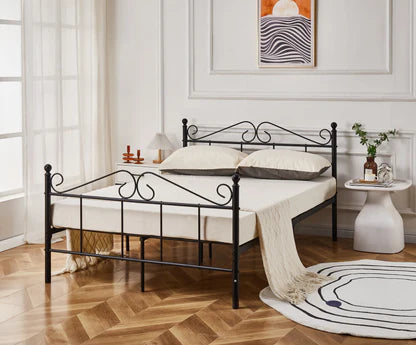 Black metal bed frame in a bedroom with wooden floor and white walls.
