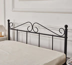 Black metal bed frame with decorative scrollwork against a white wall.