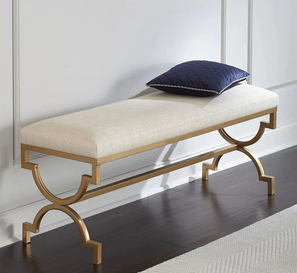 Decorative bench with gold frame and white cushion on a wooden floor.