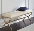 Decorative bench with gold frame and white cushion on a wooden floor.
