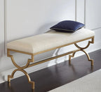 Decorative bench with gold frame and white cushion on a wooden floor.