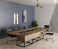 Modern conference room with a long wooden table and chairs against a gray wall.