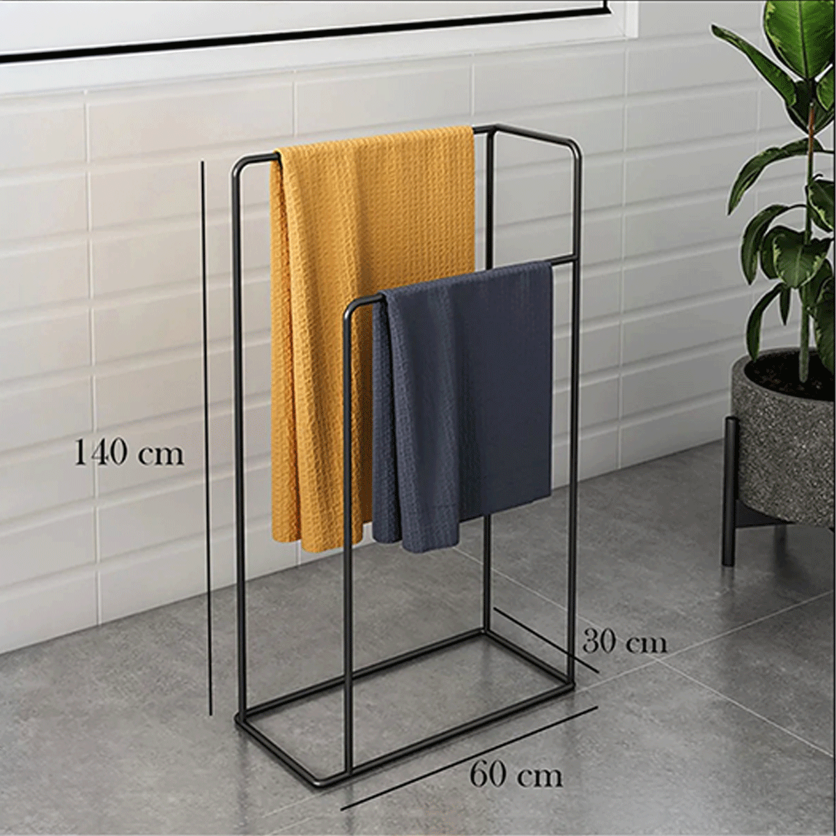 Black metal towel rack with yellow and gray towels against a tiled wall.