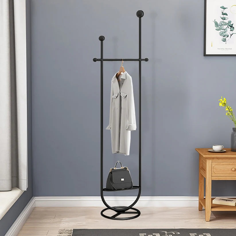 Black metal coat rack with a coat and handbag against a gray wall.