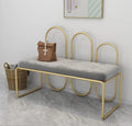Modern bench with gold frame and gray cushion in a room setting.
