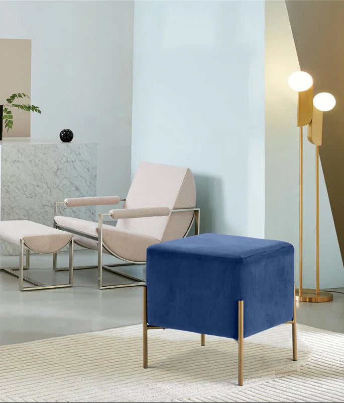 Modern living room with a beige armchair, blue ottoman, and gold floor lamp.