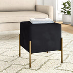 Black cube-shaped side table with gold legs in a living room setting.