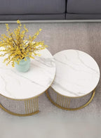 Marble coffee table with gold legs and a vase of yellow flowers on a gray carpet.