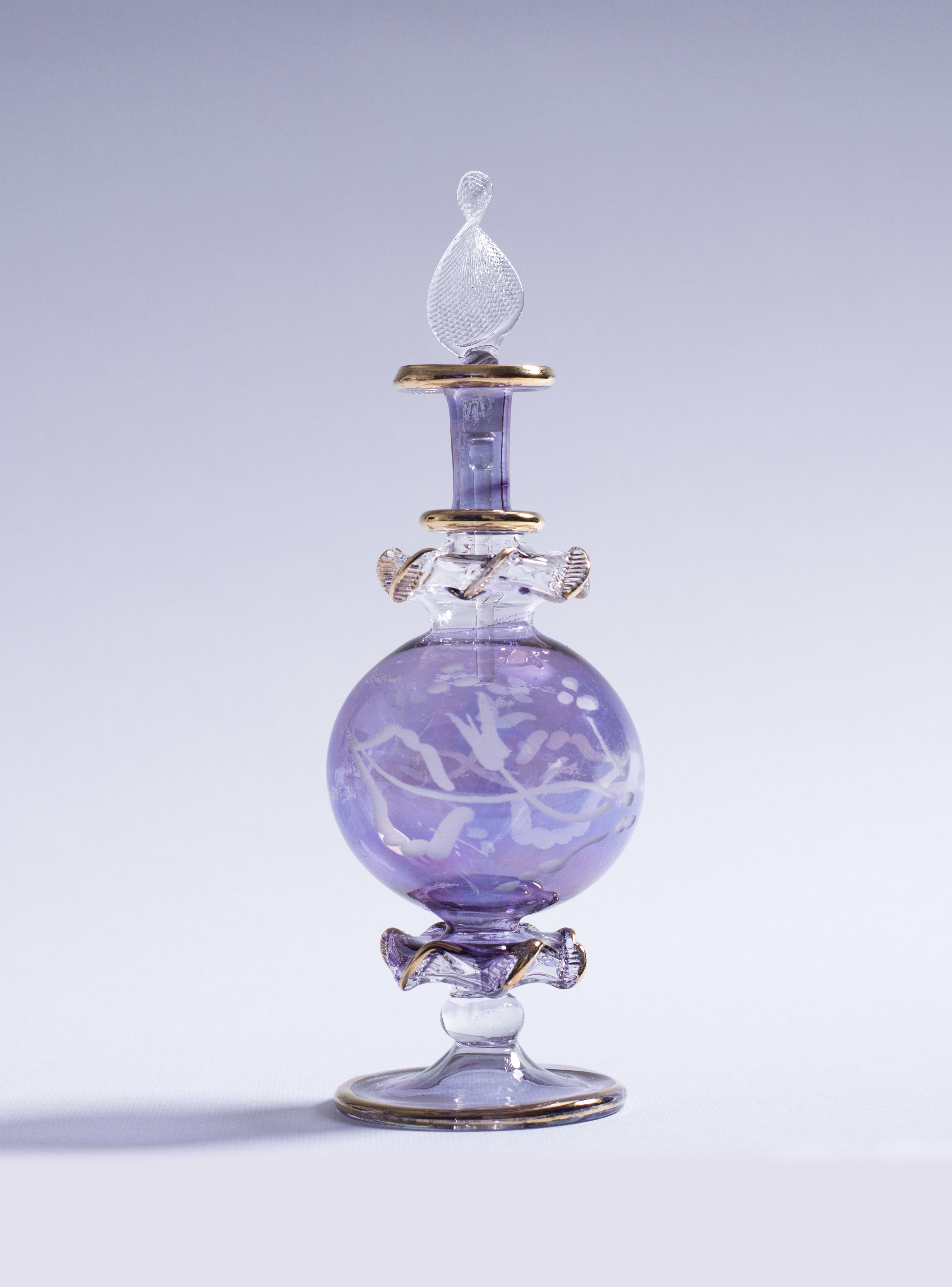 Decorative glass bottle with intricate design on a light gray background