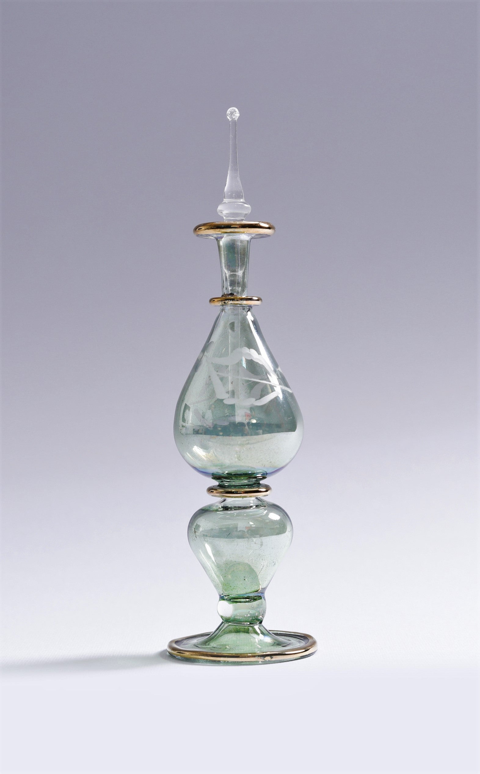 Decorative glass bottle with gold accents on a gray background