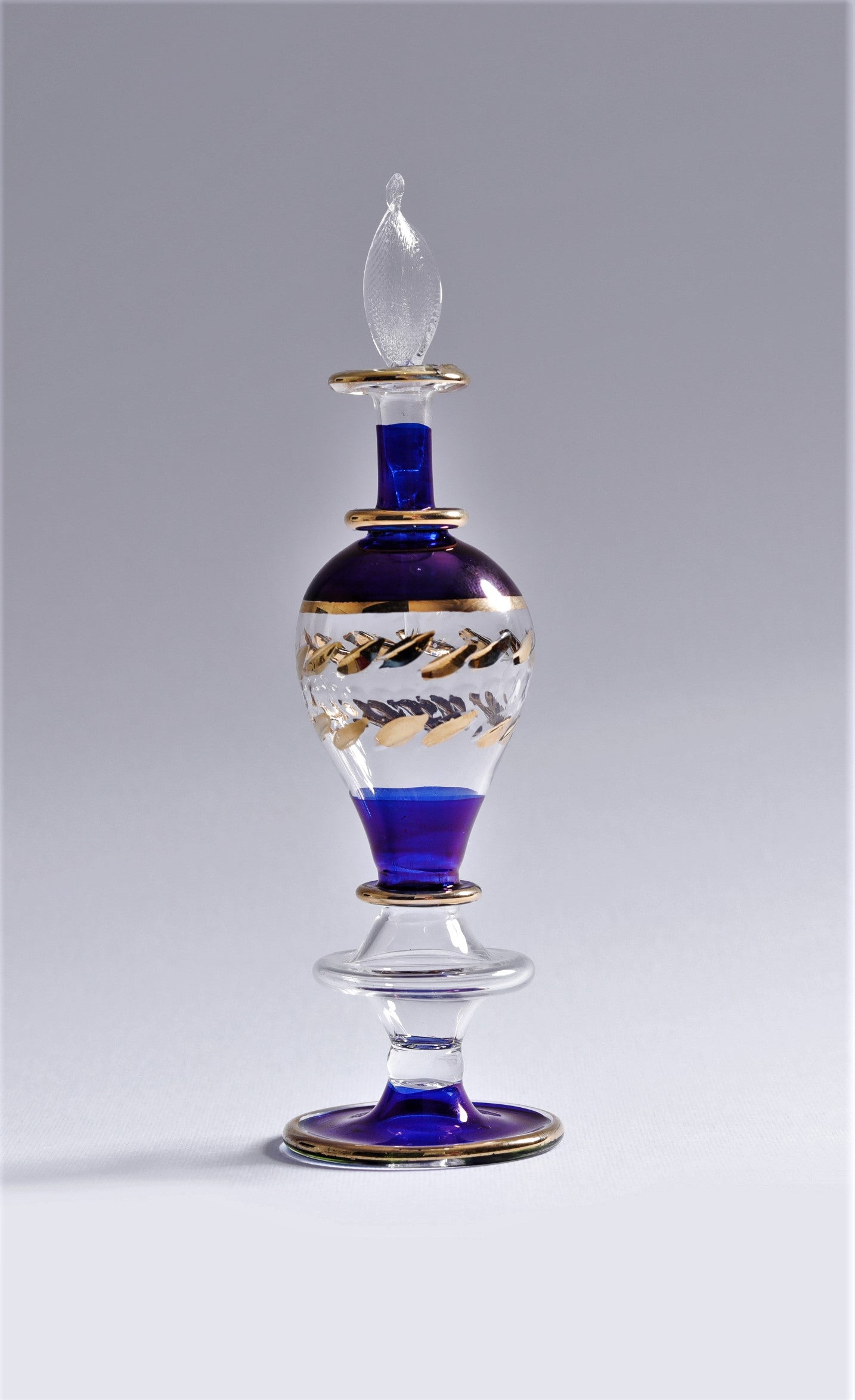 Decorative glass bottle with blue and gold accents on a gray background