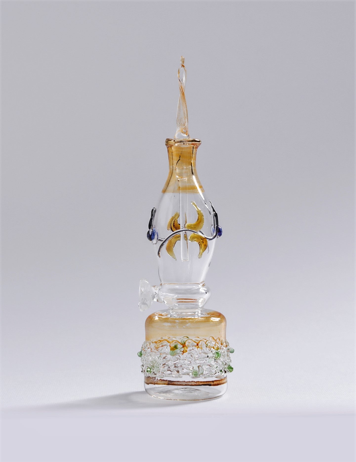 Glass smoking accessory with gold and white design on a gray background