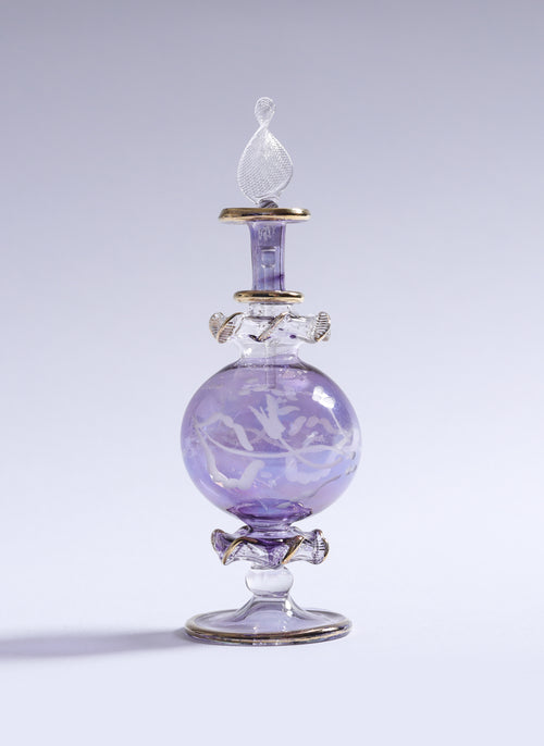 Decorative glass bottle with a purple liquid on a light gray background