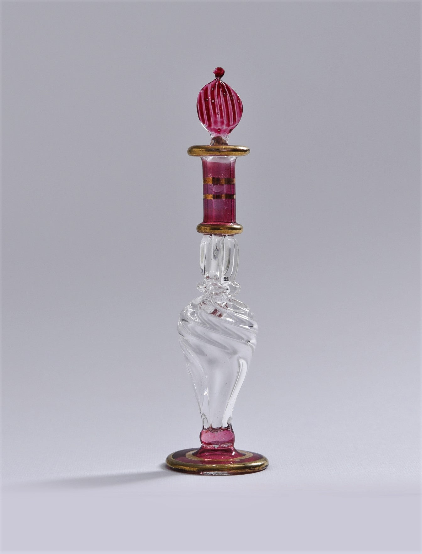 Decorative glass bottle with a red stopper on a gray background