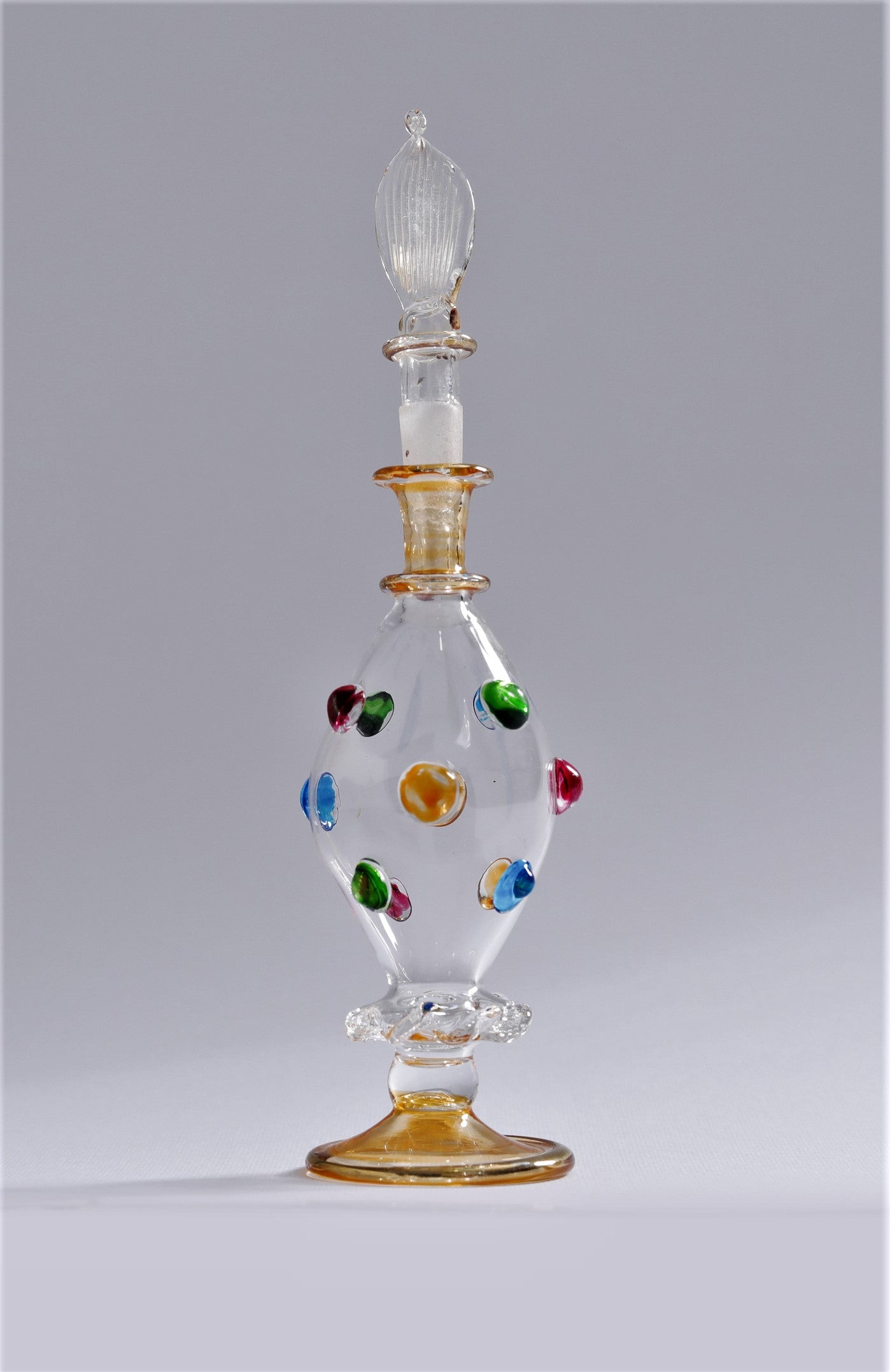 Decorative glass bottle with colorful beads on a gray background