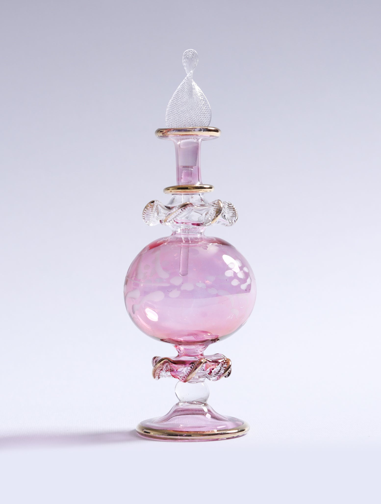 Pink glass bottle with a decorative design on a light gray background